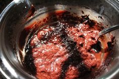 a metal bowl filled with red sauce on top of a table