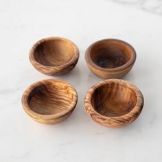 four wooden bowls sitting on top of a white counter