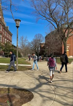 several people walking on the sidewalk near a lamp post