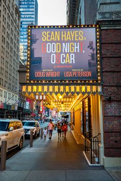 people are walking down the sidewalk in front of an outdoor theater sign that reads, dear night oscar