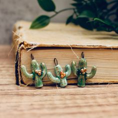 three green cactus charms sitting on top of an open book