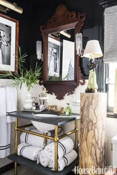 a black and white bathroom with gold fixtures, marble counter top, mirror, sink and towels on the floor