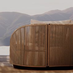 a large brown wicker couch sitting on top of a wooden floor next to mountains