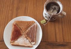 a white plate topped with two pieces of toast next to a cup of coffee on top of a wooden table