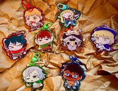 six anime keychains sitting on top of a piece of brown paper with the same character