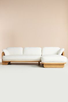 a white couch sitting in front of a pink wall