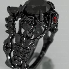 a black skull ring with a red stone in the center