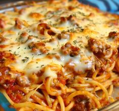 a casserole dish with meat, cheese and sauce in it on a blue plate