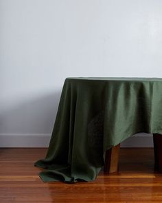 a green table cloth on top of a wooden chair in front of a white wall