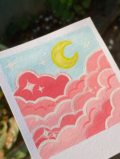 a hand holding up a card with an image of the moon and clouds