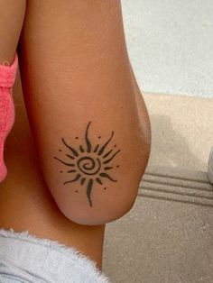 a woman's back with a tattoo on her left arm and the sun in the middle