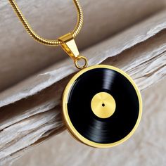 a gold necklace with a black record on it