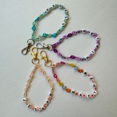 four bracelets with name charms on them sitting next to each other in different colors