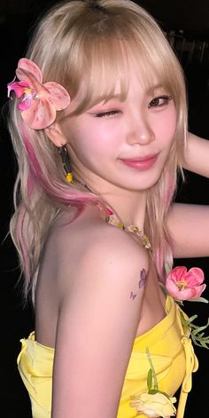 a woman with blonde hair wearing a yellow dress and pink flowers in her hair is posing for the camera