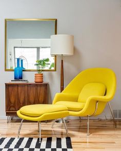 a living room with a yellow chair and ottoman next to a mirror on the wall