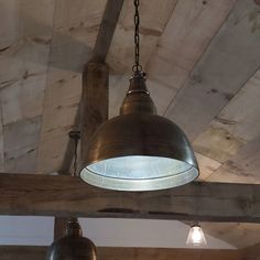 two lights hanging from the ceiling in a room with wood paneled walls and beams