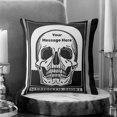 a black and white photo of a cushion with a skull on it, next to a candle