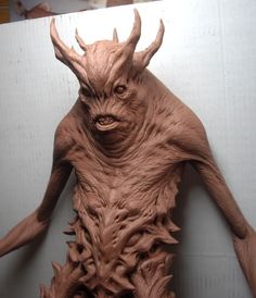 a clay sculpture of a creature with horns and claws on it's back legs