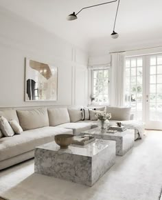 a living room with white walls and marble coffee table in front of the sectional couch