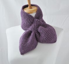 a purple knitted scarf on a white mannequin necktie with a wooden hanger