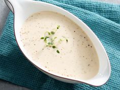 a white bowl filled with soup sitting on top of a blue cloth next to a spoon