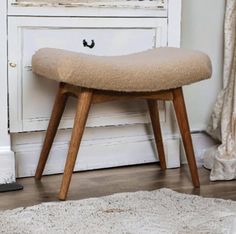 a wooden bench sitting on top of a white rug in front of a cabinet and window