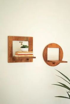 there are two wooden shelves on the wall next to a potted plant and a mirror