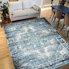 a living room filled with furniture and a rug on top of a hard wood floor