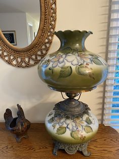 a green vase sitting on top of a wooden table next to a bird figurine