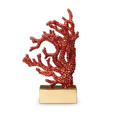 a red coral sculpture sitting on top of a wooden block in front of a white background