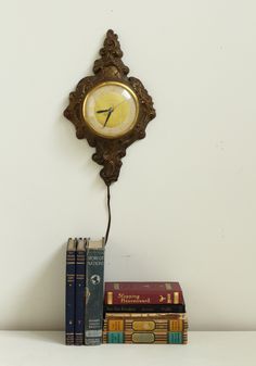 a clock sitting on top of a shelf next to books