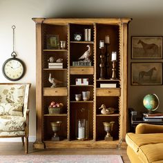 a living room filled with furniture and a clock on top of a wooden book shelf