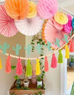 colorful paper fans and tassels are hanging from the ceiling above a party table