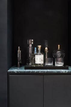 an assortment of liquor bottles sitting on top of a counter in front of a black wall