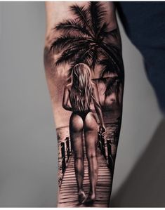 a person with a black and white tattoo on their arm is standing next to a palm tree