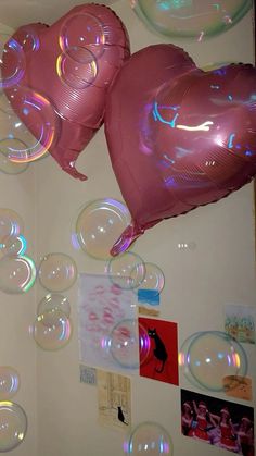 two heart shaped balloons floating in the air next to pictures and posters on a wall