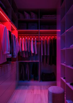 the closet is lit up with red lights and clothes hanging on shelves, along with a stool