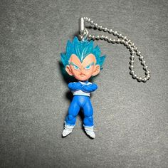 a keychain with a blue dragon figure on it's side and a chain attached to it