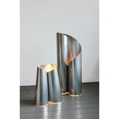 two metal vases sitting on top of a wooden floor