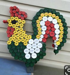 a rooster made out of bottle caps on the side of a house