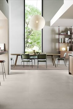 an open kitchen and dining room area with large windows, wooden furniture and modern lighting fixtures