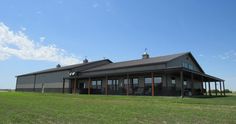 a large gray building sitting on top of a lush green field next to a blue sky