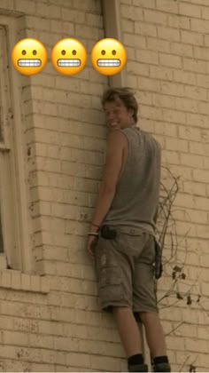 a man leaning against a brick wall with three emoticions on the window sill