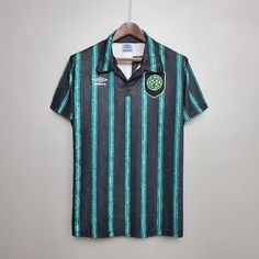 a green and black striped shirt hanging on a hanger next to a white wall