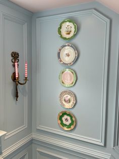 plates are arranged on the wall in this blue room with pink candlesticks and candle holders