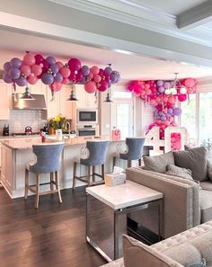 a living room filled with lots of furniture and balloons hanging from the ceiling above it