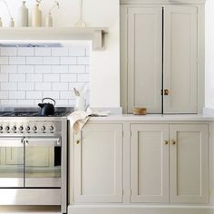 a kitchen with an oven, stove and cupboards in white painted wood paneling