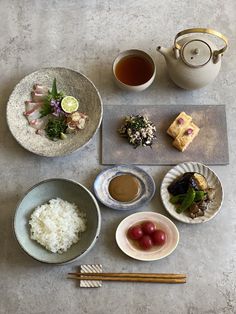 a table topped with plates and bowls filled with different types of food next to chopsticks