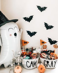 a table topped with lots of halloween items next to a giant white balloon and bats