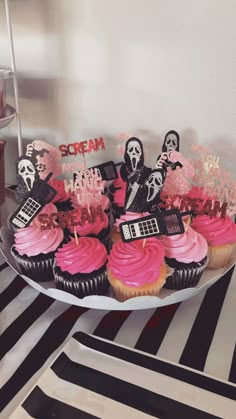 cupcakes decorated with pink frosting and spooky decorations on a plate